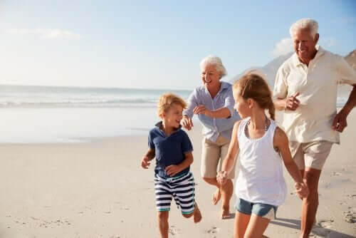 morföräldrar leker med barnbarn på strand