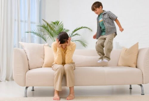 Utsläckningstekniken: pojke hoppar i soffan bredvid uppgiven mamma