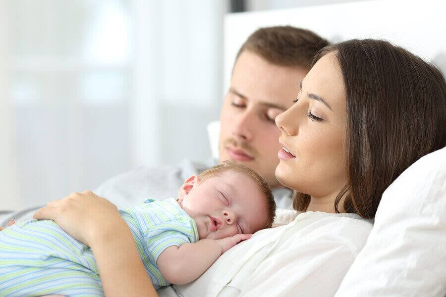 barns genetik: mamma och pappa i säng med en baby