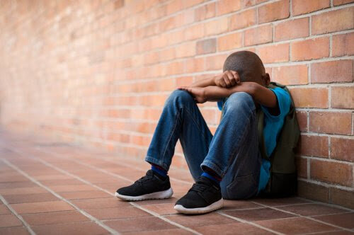 Självskadebeteende hos tonåringar: tonåring sitter hopsjunken på golvet