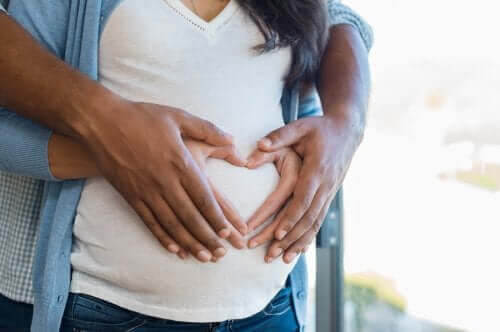 kosttillskott för gravida: man och gravid kvinna håller om den gravida magen med händer som bildar ett hjärta