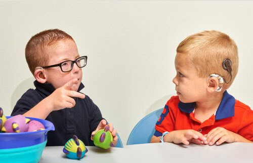 dövhet och hörselskador: två barn med hörapparater talar teckenspråk