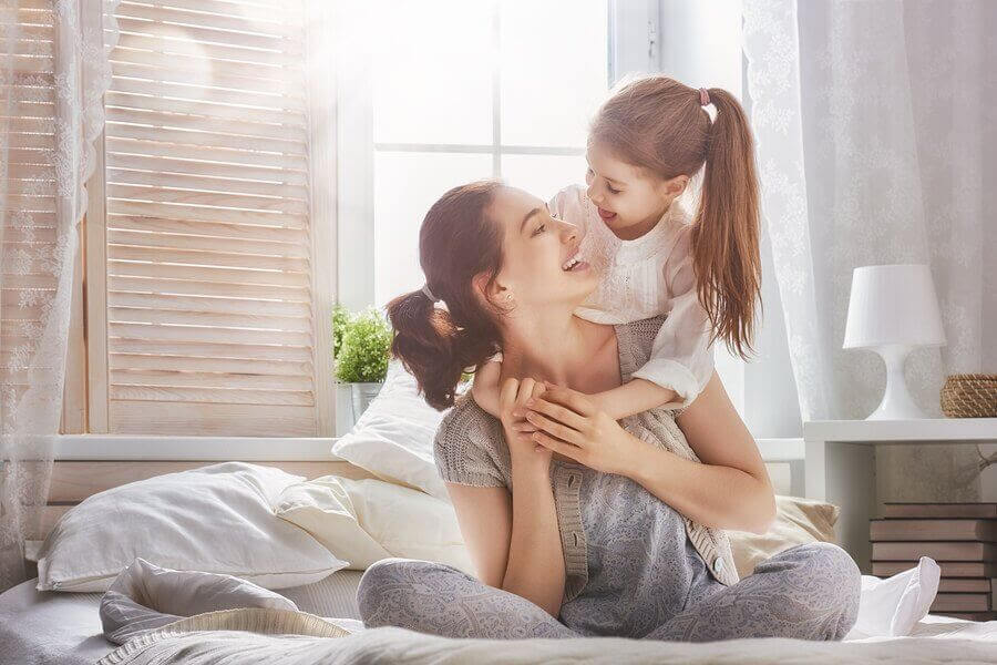 mamma och dotter leker på säng