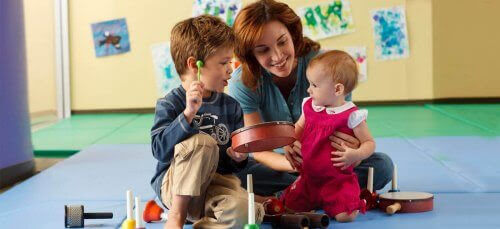 ditt barns kreativitet: pojke och kvinna underhåller baby med tamburin