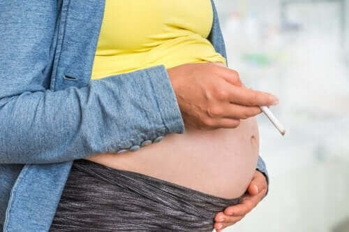 gravid kvinna håller cigarrett