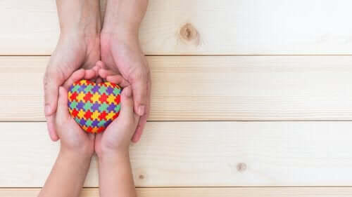 skolgång för barn med autism: barnhänder och vuxens händer håller i leksakshjärta