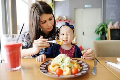 barn att äta bra: baby gör grimas när mamma försöker mata henne