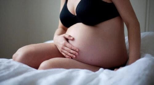 Blivande mödrar: gravid kvinna sitter på säng