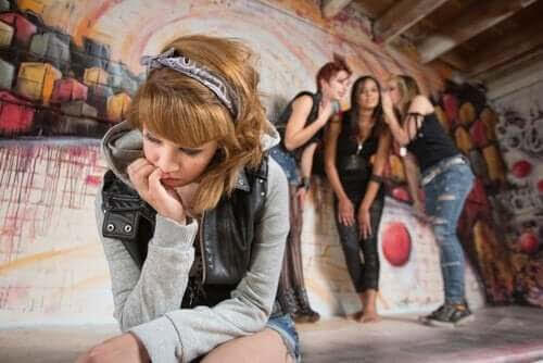 Subkulturer för ungdomar: ung tjej i förgrunden med grupp av ungdommar som viskar i bakgrunden
