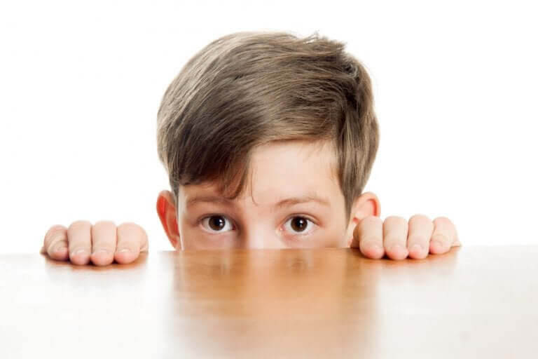 blyga och introverta barn: pojke tittar upp över bordskant