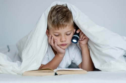 dåliga studievanor: pojke läser med ficklampa