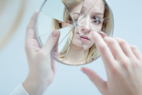 En osäker tonåring tittar i en krossad spegel.