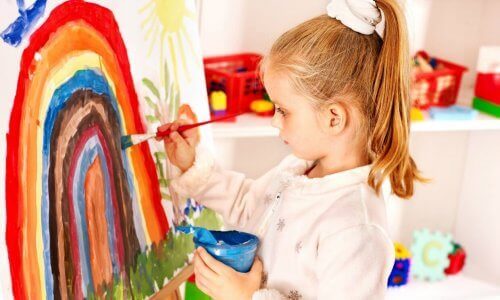 Ett barn som målar en regnbåge.