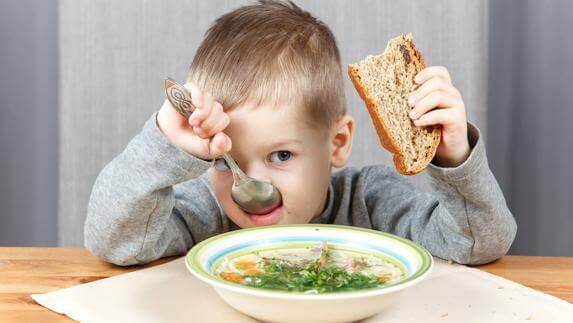 Ett barn äter hälsosam soppa.