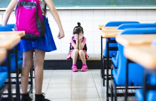 säkerhetsregler: ledsen flicka på golvet i klassrum