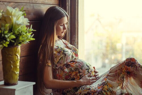 förlossningen har börjat: gravid kvinna sitter i fönster