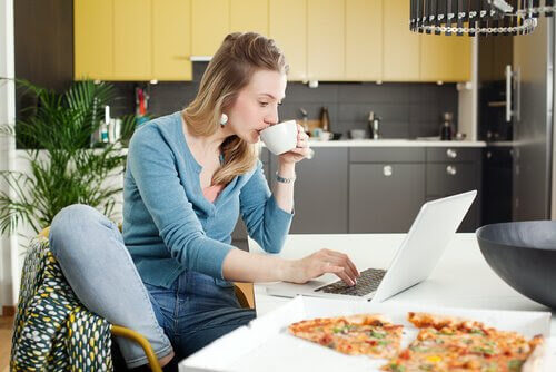 mamma med laptop i kök med pizza