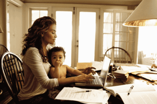 mödrar som arbetar hemifrån: mamma vid dator med baby i famnen