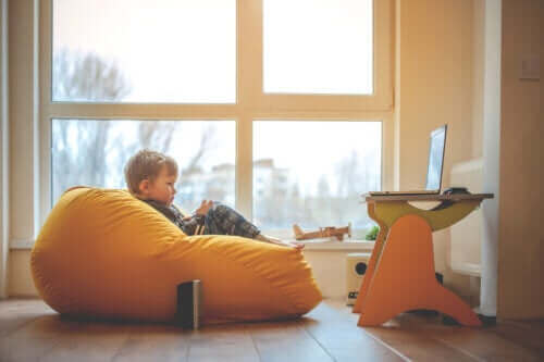 Ett barn sitter i en sittsäck och ser på tv.