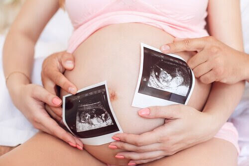 sitt barns kön: gravid kvinna med ultraljudsbilder framför magen