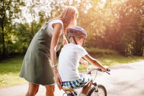 uppmuntrar positivt beteende: mamma hjälper barn cykla