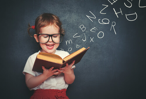 lära sig att läsa: barn med bok framför svart tavla