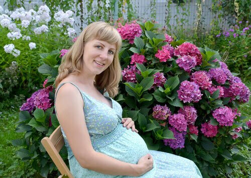 sommarmode för gravida: gravid kvinna framför blommande buske