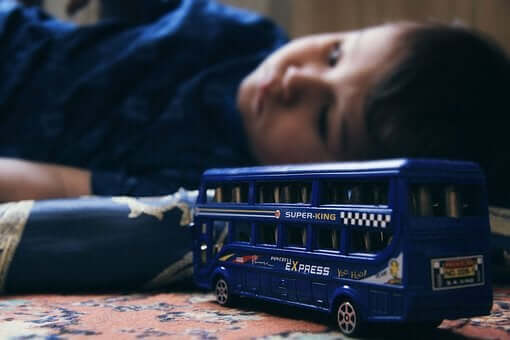 Ett barn med emotionella problem ligger bredvid sin leksaksbil.
