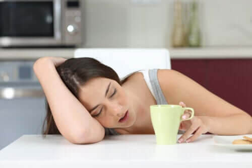 tonåring är utmattad och stressad: tonåring sover mot bord bredvid kaffekopp