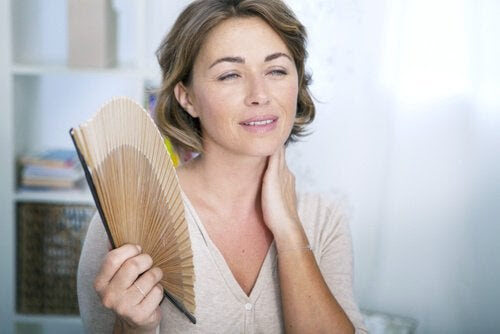 För tidig klimakterium: kvinna fläktar sig med solfjäder