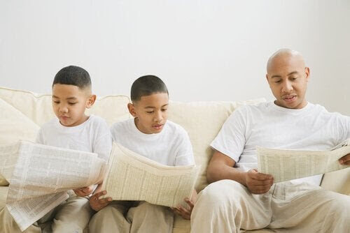 genom modellering: två barn och en pappa läser tidning i soffa