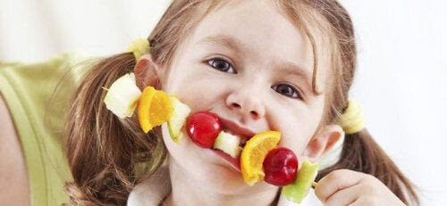 frukt tilltalande för barn: flicka äter frukt på spett