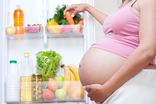 mellanmål för tredje trimestern: gravid kvinna vid kylskåp
