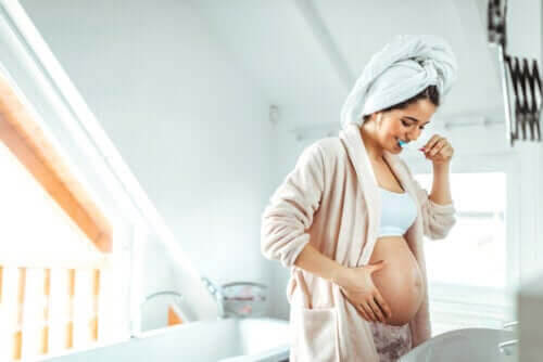 dig som en mamma: gravid kvinna borstar tänderna och känner på sin mage