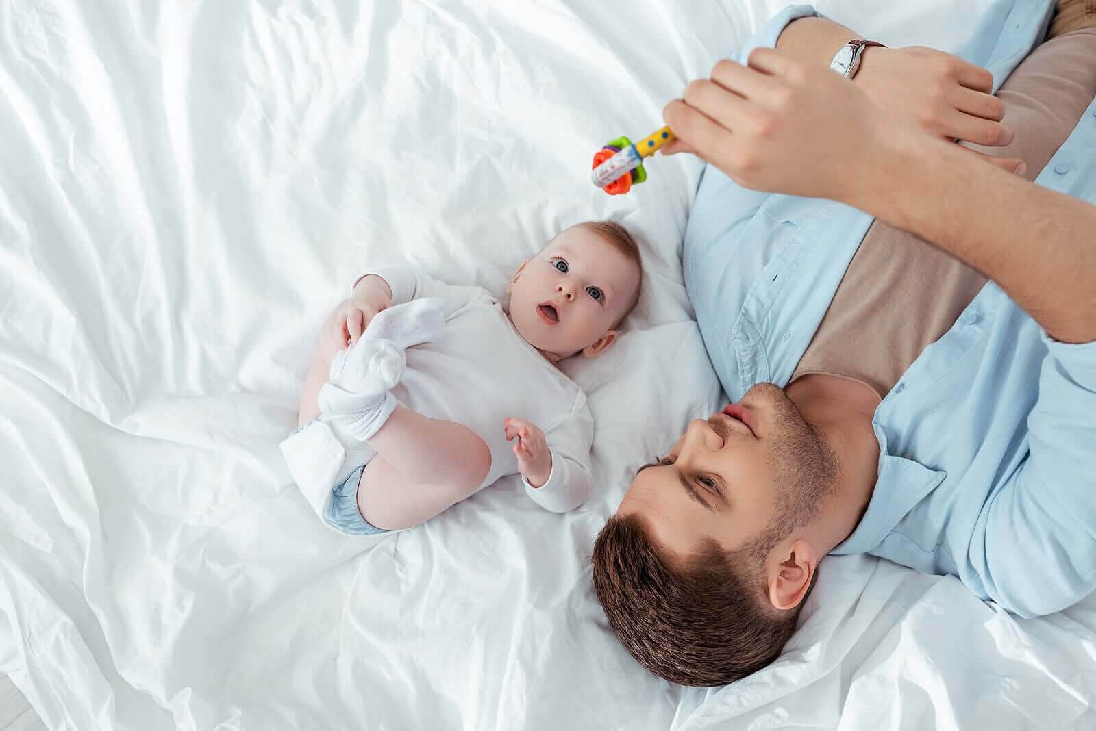 känslomässiga band och musikinstrument: pappa visar skallra för baby