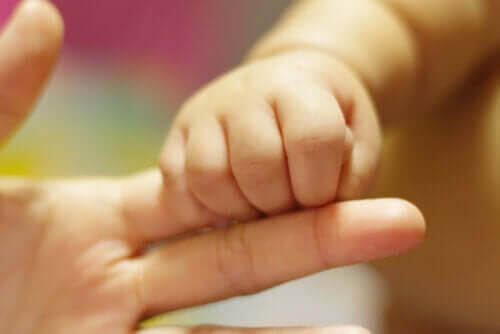 baby håller om fingret på mamma