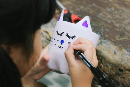 pyssel med plastflaskor: flicka målar på plastflaska