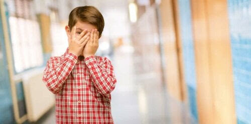 skadlig skam: pojke döljer ansiktet i händerna