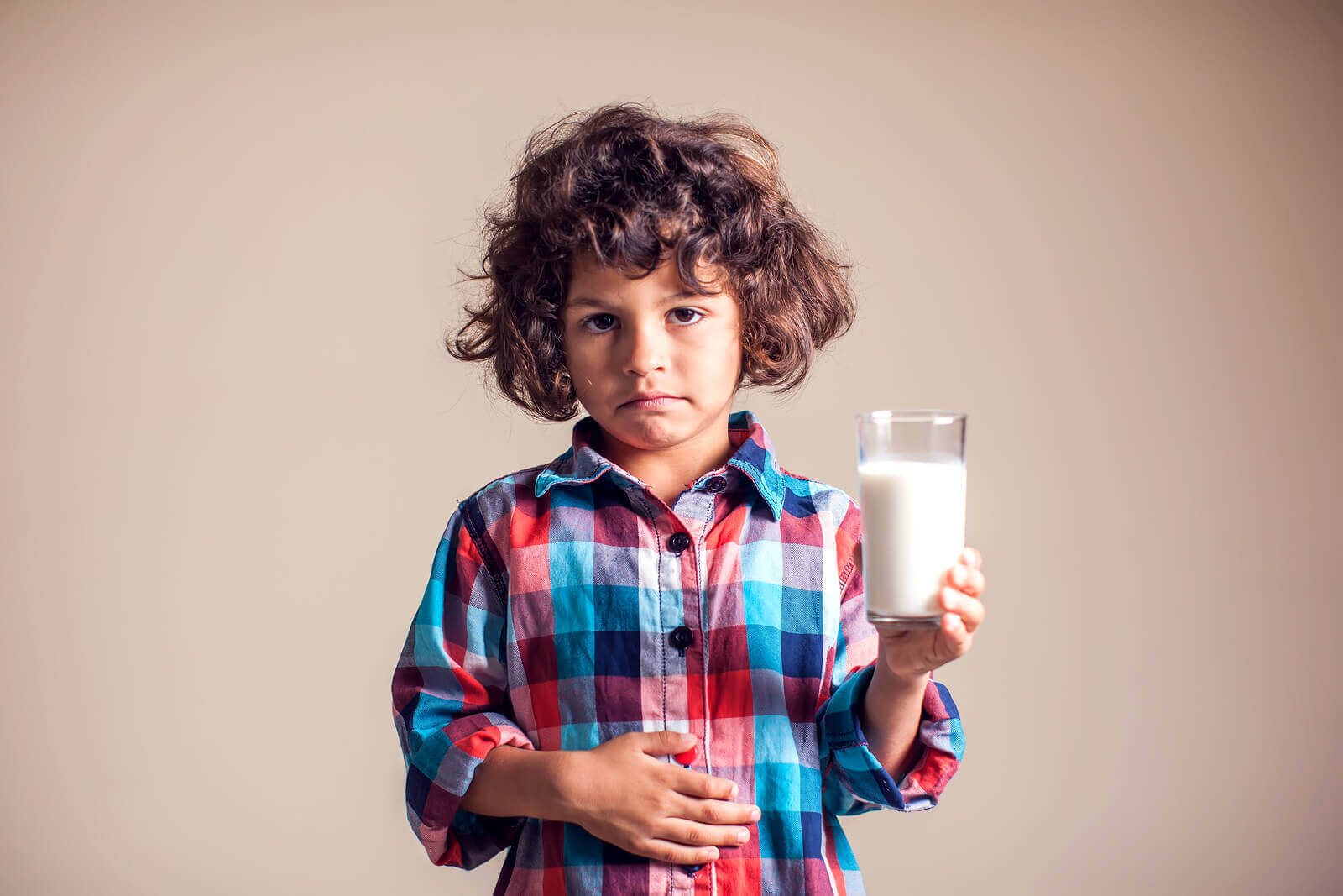 allergi mot komjölksprotein: pojke med ett glas mjölk håller sig för magen