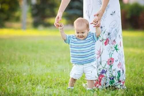 Benfrakturer hos småbarn: mamma hjälper baby gå på äng
