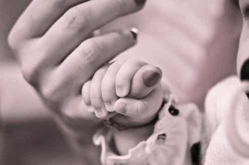 baby håller i mammas hand