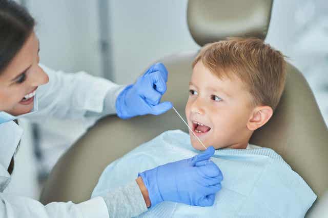 Tandläkare rengör barns tänder med tandtråd.
