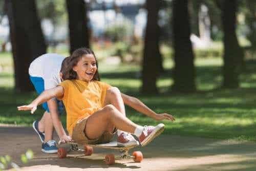 Syskon leker med en skateboard.