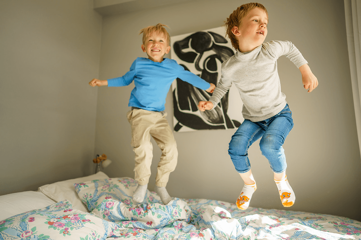 Två pojkar hoppar i en säng.
